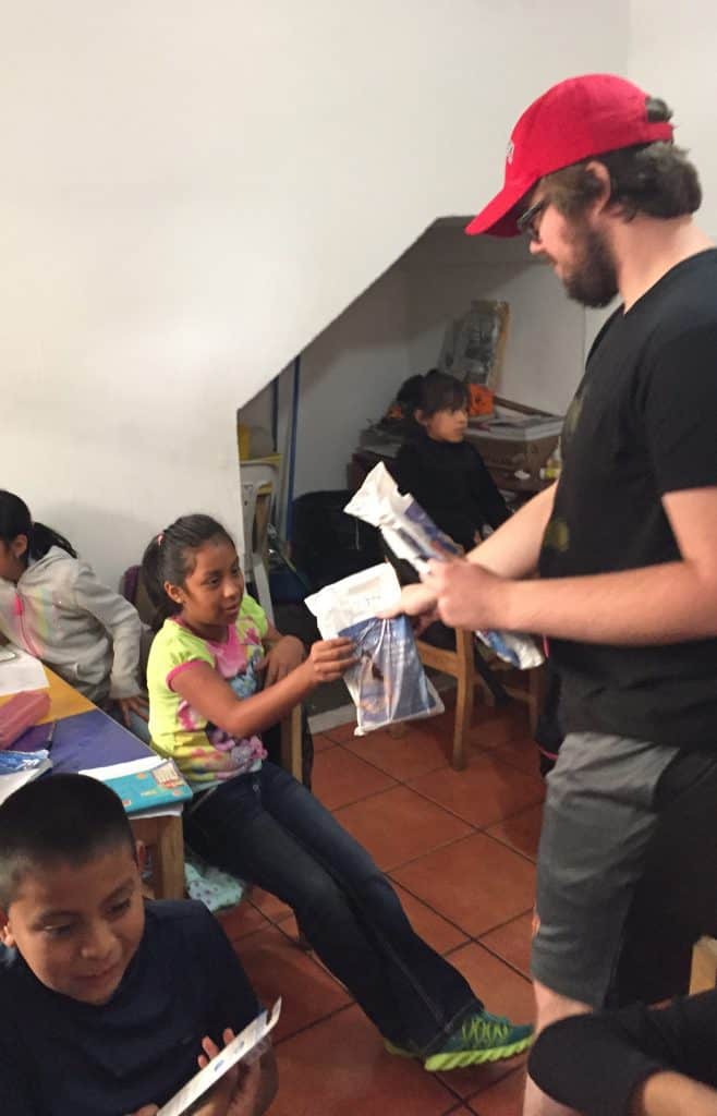 Robert Sullivan hands a dental hygiene kit to a third grader at Escuela Integrada.